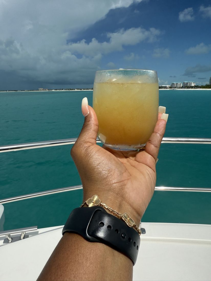 A drink held up over turquoise water on a boat at a past Virgoat Bash